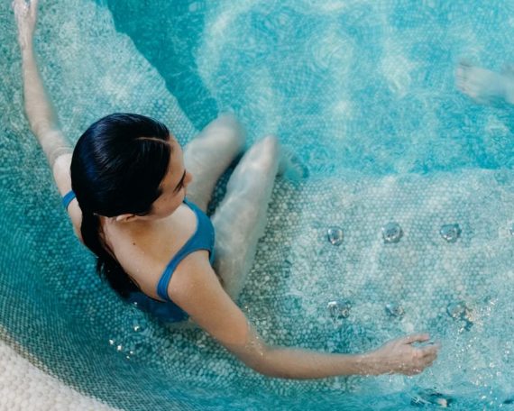 Aerial view of a woman in a blue swimsuit lounging in a swimming pool, capturing a serene moment.