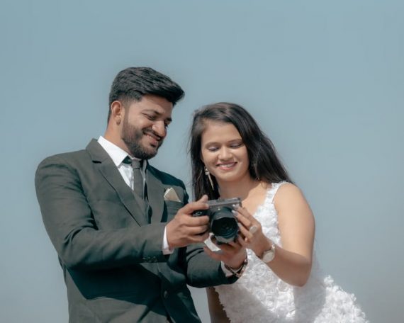 Smiling couple reviewing photos on camera during an outdoor pre-wedding shoot.